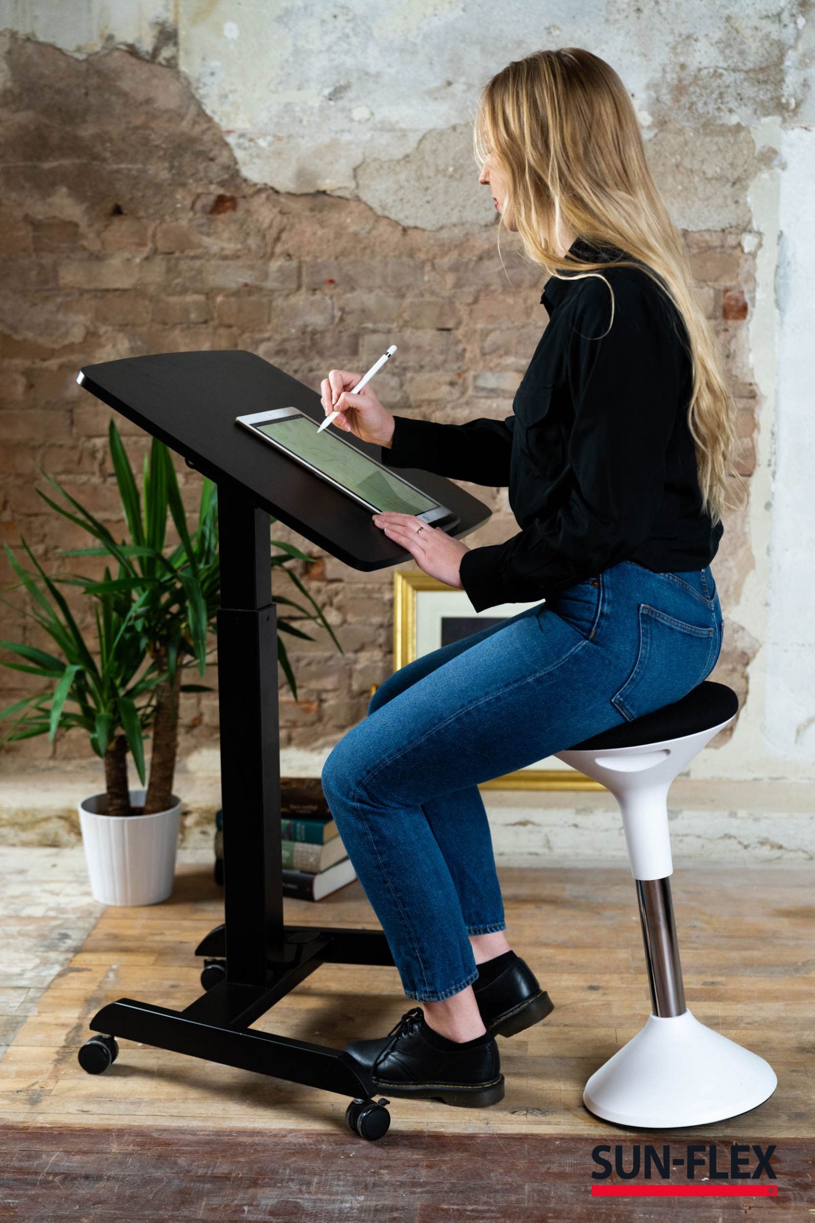 kvinna sitter och skissar med hjälp av den tiltande funktionen på easy desk pro skrivbord