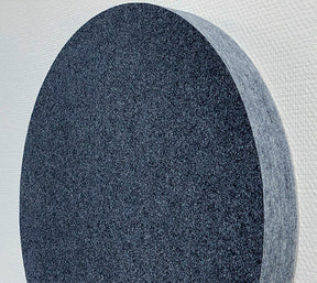 närbild på cirkelformad mörkgrå väggabsorbent placerad på vitt vägg